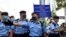 Police officers raise a warning flag against supporters gathered outside a court in Hong Kong Monday, March 1, 2021. Hong Kong police on Monday brought 47 pro-democracy activists to court on charges of conspiracy to commit subversion under the…