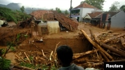 Seorang warga desa berdiri di dekat sebuah rumah yang hancur akibat longsor yang melanda desa Pasir Panjang, Brebes, 23 Februari 2018. (Foto: Antara/OKy Lukmansyah/via REUTERS).