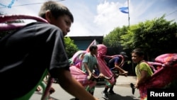 Niños nicaraguenses disfrazados juegan en la calle antes de las festividades en honor del santo patrón de la nación Santo Domingo de Guzmán. Managua, 1 de agosto de 2018.