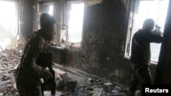 Rebel fighters take positions inside a damaged building during clashes with forces loyal to Syria's President Bashar al-Assad in Aleppo's historic citadel Dec. 7, 2014.