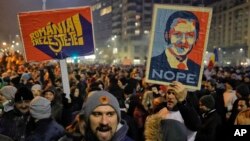 Demonstran membawa poster pemimpin partai penguasa Partai Sosial Demokrat, Liviu Dragnea, dan poster bertuliskan "Romania, Bangun" dalam protes di Bukares (1/2). (AP/Vadim Ghirda)