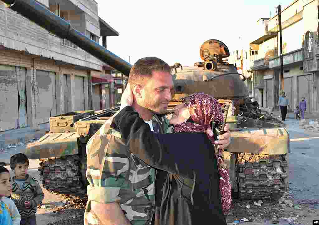 A Syrian woman kisses a soldier from the Free Syrian Army in front a destroyed Syrian army forces tank that was attacked during clashes between the Syrian government forces and the Syrian rebels, in Rastan, Homs, March 21, 2012. (AP) 