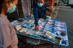 FILE - A newspaper seller points at a front page of a newspaper in Yangon, Myanmar, Feb. 2, 2021.