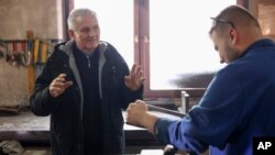 Ratni pronalazač, inženjer i bivši učitelj Aziz Lepenica, lijevo, daje upute učenika u srednjoškolskoj radionici u Goraždu, Bosna, ponedjeljak, 19. decembra 2022.