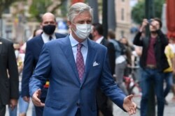 FILE - Belgium's King Philippe, wearing a face mask, walks down a main shopping street in Brussels, May 10, 2020.