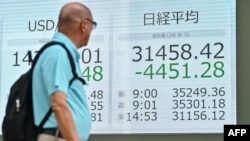 A pedestrian glances at a display board showing the closing numbers after record losses on the Tokyo Stock Exchange on Aug. 5, 2024. Tokyo stocks sank more than 12%, battered by a resurgent yen and weak U.S. jobs data that fueled fears of a recession in the world's top economy. 