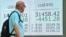 A pedestrian glances at a display board showing the closing numbers after record losses on the Tokyo Stock Exchange on Aug. 5, 2024. Tokyo stocks sank more than 12%, battered by a resurgent yen and weak U.S. jobs data that fueled fears of a recession in the world's top economy. 