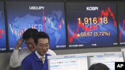 Currency traders react in front screens at the Korea Exchange Bank headquarters in Seoul, South Korea, December 1, 2011.