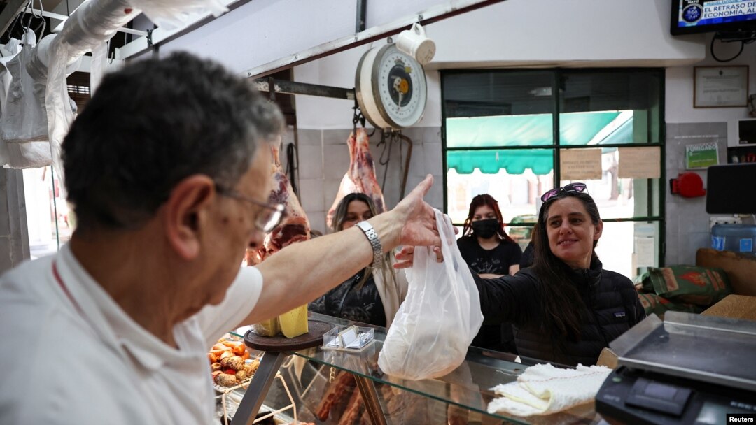 Butcher Dario Barrandeguy gives an order of meat to a customer at his shop, in Buenos Aires, Argentina June 10, 2024. Inflation has hit Argentines hard.