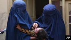 FILE - A health worker, right, administers a polio vaccine to a child in a neighborhood of Jalalabad, east of Kabul, Afghanistan, Oct. 29, 2024. 