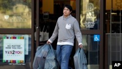 A man carries bags out of a department store in Alameda, California, Dec. 17, 2015. U.S. consumer spending rebounded in November after a weak showing in October while a key inflation gauge posted the fastest year-over-year increase in 11 months. 