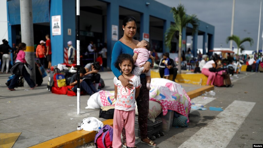 Venezuelan migrant Nemesis Ramirez, 22, poses for a picture with her children, while they wait to process their documents at the Ecuadorian-Peruvian border service center, before they continue their journey, June 17, 2019.