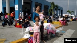 FILE - Venezuelan migrant Nemesis Ramirez, 22, poses for a picture with her children, while they wait to process their documents at the Ecuadorian-Peruvian border service center, before they continue their journey, June 17, 2019.