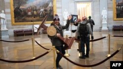 WASHINGTON, DC - JANUARY 06: A pro-Trump protester carries the lectern of U.S. Speaker of the House Nancy Pelosi through the Roturnda of the U.S. Capitol Building after a pro-Trump mob stormed the building on January 06, 2021 in Washington, DC…