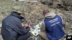 In this photo provided by Kharkiv Regional Prosecutor's Office, war crime prosecutors inspect fragments of bomb after Russia's attack in Kharkiv, Ukraine, Wednesday, April 24, 2024