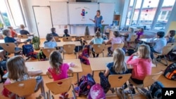 File picture taken Aug.3, 2020 shows teacher Francie Keller welcoming the pupils of class 3c in her classroom in the Lankow primary school to the first school day after the summer holidays in Schwerin, Germany, 2020