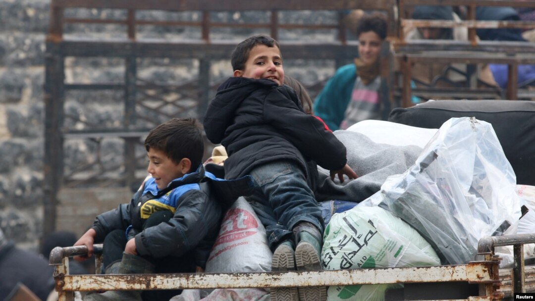 Anak-anak laki-laki duduk di atas tumpukan barang, menunggu evakuasi dari daerah pemberontak di Aleppo timur, Suriah (16/12). 