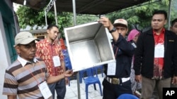 Electoral workers show an empty box before the opening station for voters during the gubernatorial election in Jakarta, Indonesia, Feb. 15, 2017.