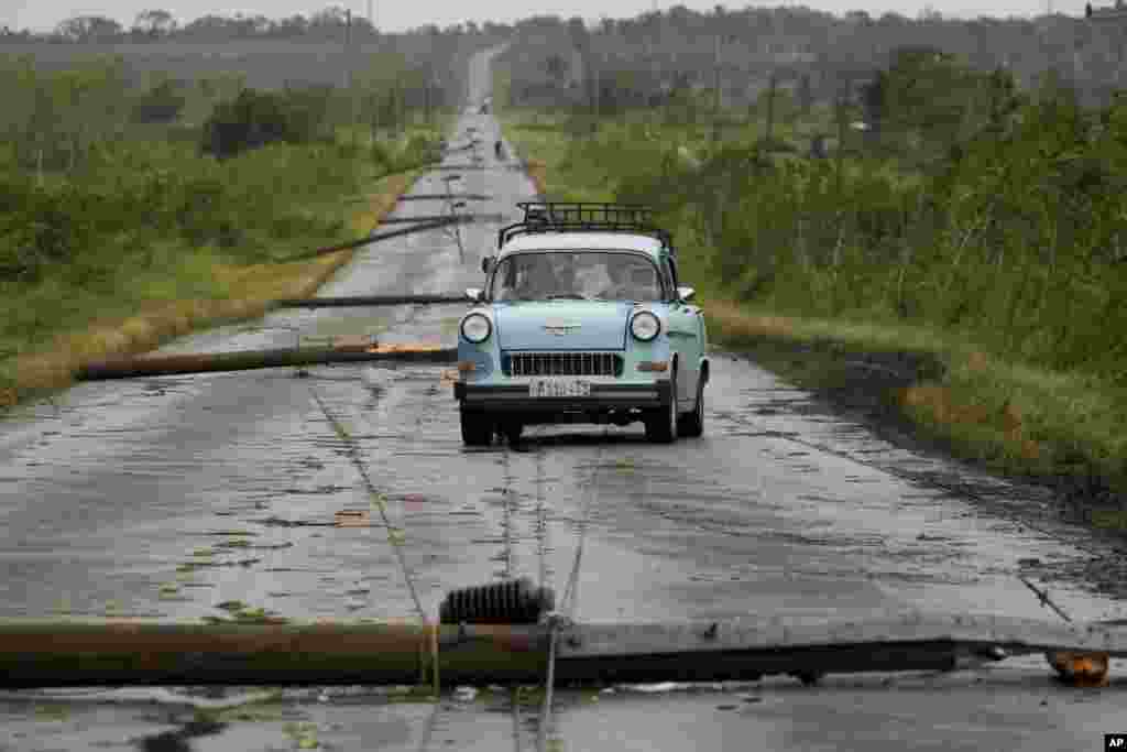 People drive along a road littered with fallen power lines after the passing of Hurricane Rafael in San Antonio de los Banos, Cuba.