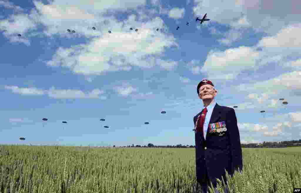British World War II veteran Frederick Glover looks at soldiers parachuting down during a D-Day commemoration paratroopers launch event in Ranville, northern France, on the eve of the 70th anniversary of the World War II Allied landings in Normandy.