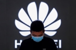 FILE - In this Aug. 31, 2020, photo, an employee wearing a face mask to help curb the spread of the coronavirus stands inside a Huawei flagship store in Beijing.