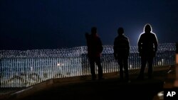 Residents stand on a hill before barriers separating Mexico and the United States, where the border meets the Pacific Ocean, in Tijuana, Mexico, Nov. 17, 2018. Many of nearly 3,000 U.S.-bound Central American migrants have reached the border with California.