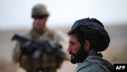 An Afghan farmer watches as U.S. Marines on the outskirts of Marjah in central Helmand, 26 Jan 2010