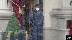 Snow falls as a police officer stands in front of the Grand Hotel Wien where closed-door nuclear talks with Iran take place in Vienna, Austria, April 6, 2021. 