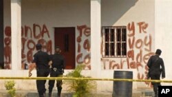 Police agents look at a message written in blood at the site of a massacre at a local ranch in the hamlet Caserio La Bomba, in La Libertad, northern Guatemala, Sunday May 15, 2011