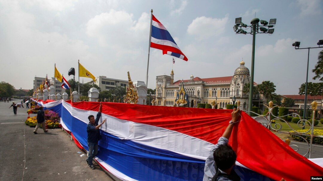 Para demonstran anti-pemerintah membungkus pintu gerbang dan pagar di sekeliling Wisma Pemerintah Thailand di Bangkok dengan spanduk raksasa berhias warna-warna bendera Thailand (13/12).
