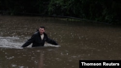 A man wades through floodwaters on a residential street near the swollen Nepean River as the state of New South Wales experiences widespread flooding and severe weather, in Sydney, Australia, March 21, 2021. 