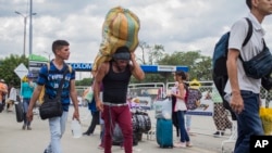 A man carries a large load on his back, with the strap around his forehead, as he works as a “lomo taxista,” or taxi of the lower back, across the border from Cucuta, Colombia to Venezuela, Sept. 20, 2019.