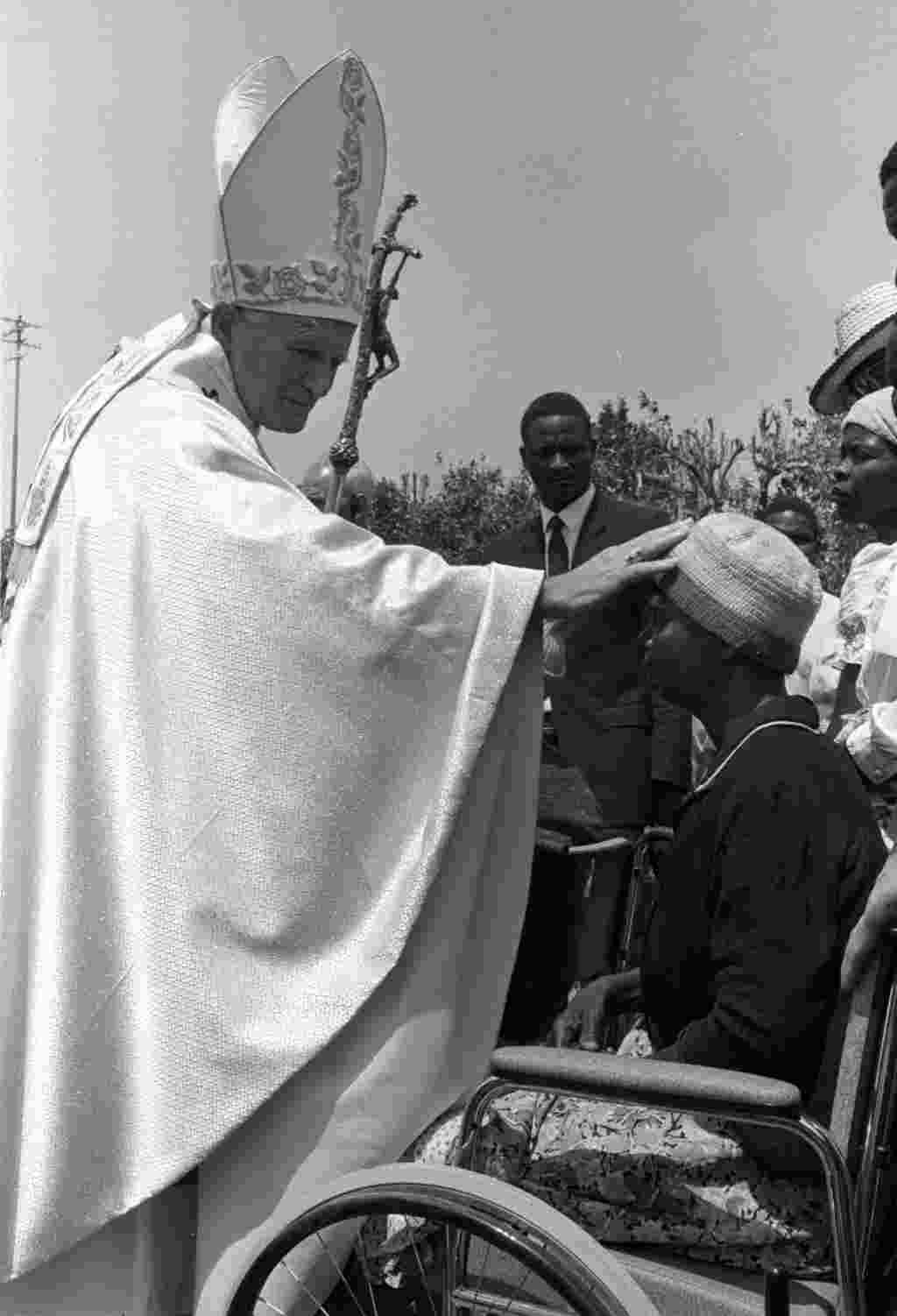 El Papa Juan Pablo II bendice a uno de los veinte mutilados víctimas de la guerra civil de Mozambique (1988).