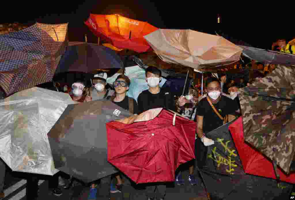 Protesters use umbrellas to block the pepper spray by police officers outside government headquarters in Hong Kong&#39;s Admiralty, Oct. 15, 2014. 