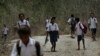 In this Oct. 22, 2018, file photo, students walk on dirt road after school in O'of village in West Timor, Indonesia. Children in this impoverished region of Indonesia often must walk long distances to school. 