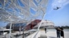 Los asistentes toman fotografías mientras un avión aterriza en el Aeropuerto Internacional de Los Ángeles (LAX) durante una vista previa de obras de arte públicas en el Intuit Dome el 11 de julio de 2024 en Inglewood, California.