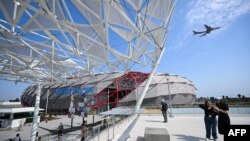 Los asistentes toman fotografías mientras un avión aterriza en el Aeropuerto Internacional de Los Ángeles (LAX) durante una vista previa de obras de arte públicas en el Intuit Dome el 11 de julio de 2024 en Inglewood, California.