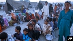 Pakistani children wait for cooked food at a camp for people displaced by floods in Sukkur, southern Pakistan. Government officials organized an event to entertain flood affected people and help them temporarily forget life at the camps, 21 Sep 2010.