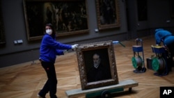 A worker moves the painting "Portrait of Antonio de Covarrubias y Leiva" by Spanish painter El Greco, at the Louvre museum, in Paris, France, Feb. 9, 2021, as the COVID pandemic gives staff a rare opportunity to tackle long-overdue refurbishments. 