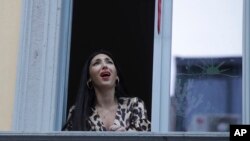 Opera singer Laura Baldassari leans out of her window to sing during a flash mob launched throughout Italy to bring people together and try to cope with the emergency of coronavirus, in Milan, Italy, March 13, 2020.