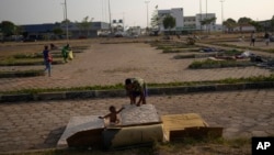 Venezuelan migrant Carlos Figuera arranges his sleeping mattresses with his son after sleeping outdoors in the parking lot of a bus terminal in Boa Vista, Roraima state, Brazil, April 7, 2023.