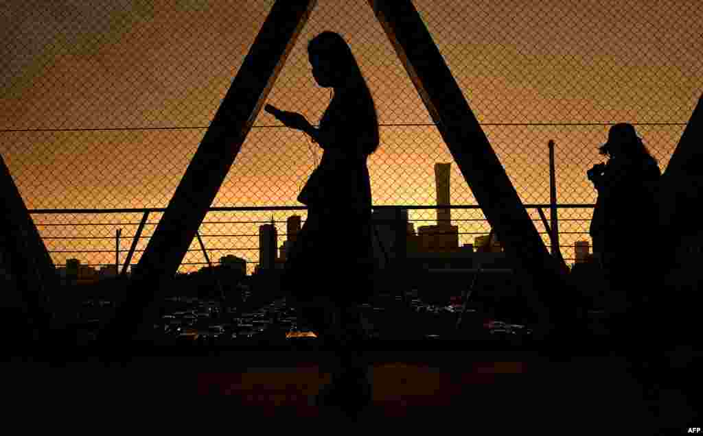 People walk on an overpass overlooking the horizon as the sun sets in Beijing on Aug. 26, 2021.
