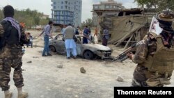 خودرویی که راکت ها از روی آن شلیک شد در پس زمینه تصویری از دو عضو طالبان. کابل