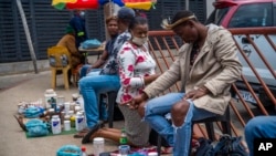 A woman consults a traditional doctor near the Baragwanath taxi rank in Soweto, South Africa, Dec. 2, 2021. Fearing vaccines, some turn to traditional doctors for COVID-19 remedies. 