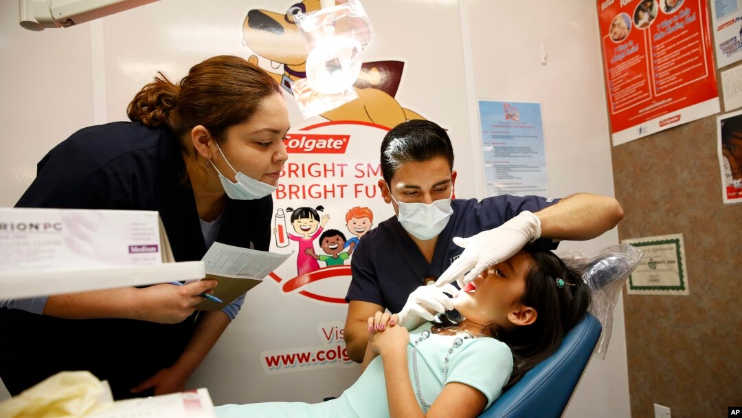 FILE - UT Health Dental School student volunteers provide a free dental screening on a child at Fiesta Mart in Houston, June 13, 2015. 