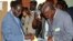 Zimbabwe's President Robert Mugabe (L) cast his vote as an election officer looks on outside Harare, July 31, 2013. 