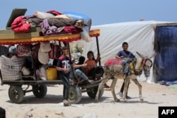 FILE—Palestinian children who fled Rafah in the southern Gaza Strip transport their family's belongings in the back of a donkey-pulled cart as they arrive to take shelter in Khan Yunis on May 12, 2024, amid the ongoing conflict between Israel and Hamas.