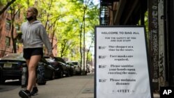 A pedestrian passes a storefront sign that lists COVID-19 protective protocols required for entry in the retail shopping district of the SoHo neighborhood of the Manhattan borough of New York, May 14, 2021.