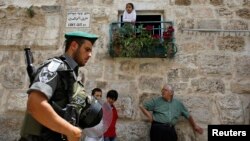 Israeli border police officer walks past Palestinians in Jerusalem's Old City before a parade marking Jerusalem Day, May 8, 2013.