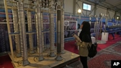 Seorang pelajar melihat mesin sentrifugal buatan lokal dalam sebuah pameran terkait pencapaian nuklir Iran di Teheran, pada 8 Februari 2023. (Foto: AP/Vahid Salemi)